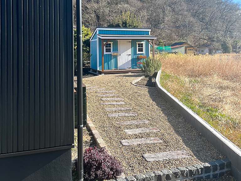 庭の長いアプローチの先に建つ、オーナーがDIYで建てた小屋。