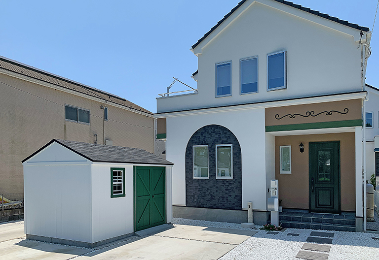住宅の外観と調和するよう白と緑に塗装された木製物置